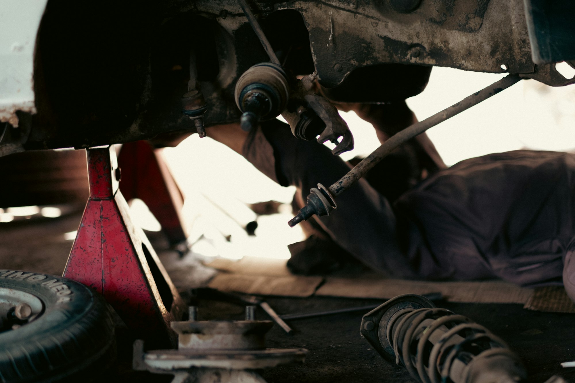 Mechanic checking suspension under a raised vehicle
